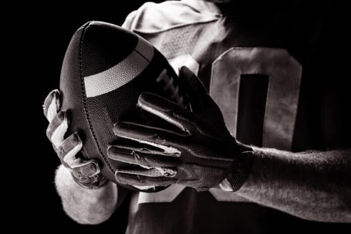 Mid section of American football player holding rugby ball