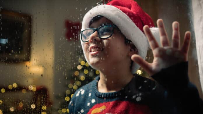 Kid watching outside window on rainy christmas night