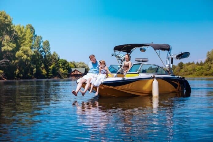 Happy father and daughter sitting on bow of boat