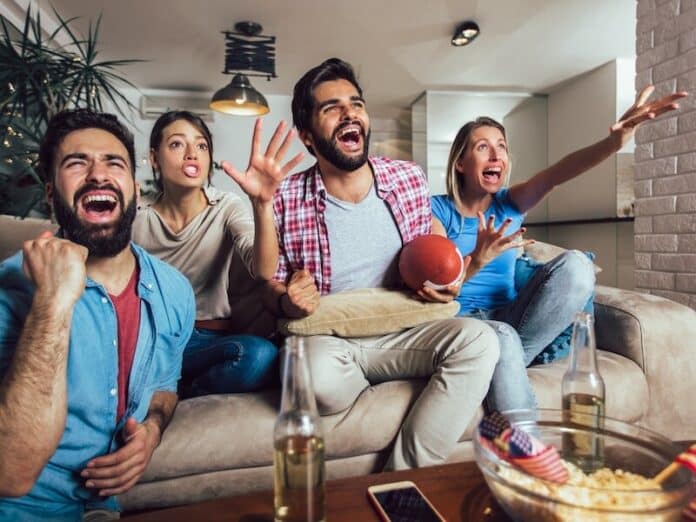 Friends cheering sport league together on tv and celebrating victory at home.Friendship, sports and entertainment concept. Game Day Snacks with Southern City Flavors