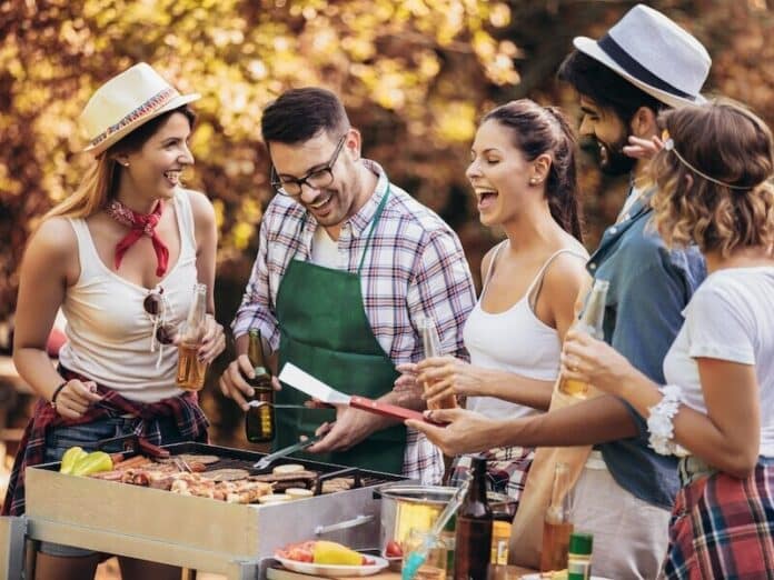 Happy friends having fun grilling meat enjoying barbecue party