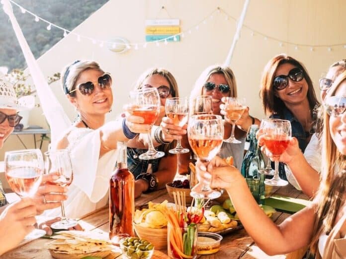 Cheerful group of happy female people clinking and toasting together with friendship and happiness - young and adult women have fun eating - food and beverage celebration concept